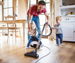 Father vacuuming cleaning with toddler and baby - feature