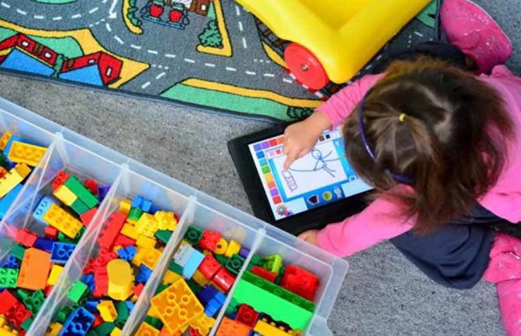 Young girl playing with ipad screen and toys - feature