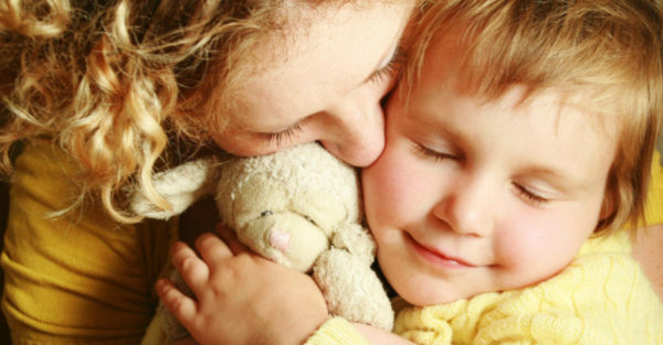 mum cuddles child with teddy bear