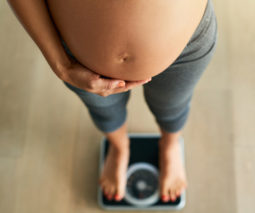 Pregnant woman standing on scales weight - feature