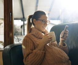 Pregnant woman drinking tea and reading phone - feature