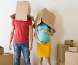 Pregnant couple with moving house boxes on their heads - feature