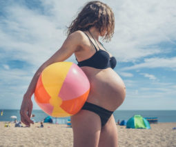 Pregnant woman on the beach holding beachball