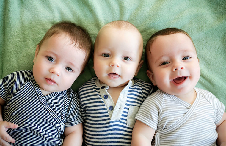 Three babies lying on the floor together - feature