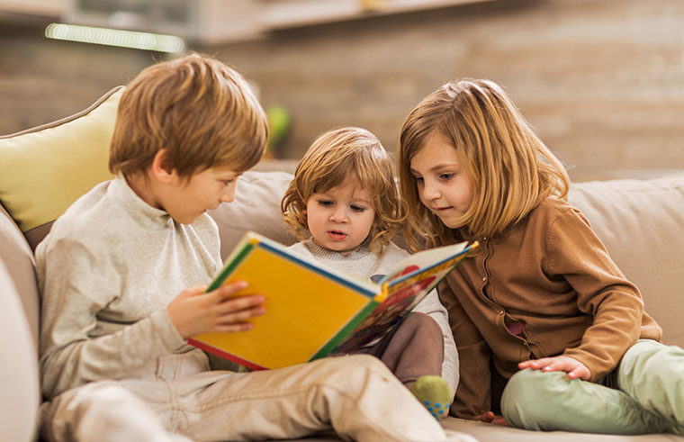 Three siblings reading a book together - feature