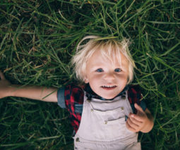 Toddler boy lying in grass - feature
