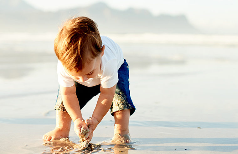 Toddler boy playing in sand on the beach