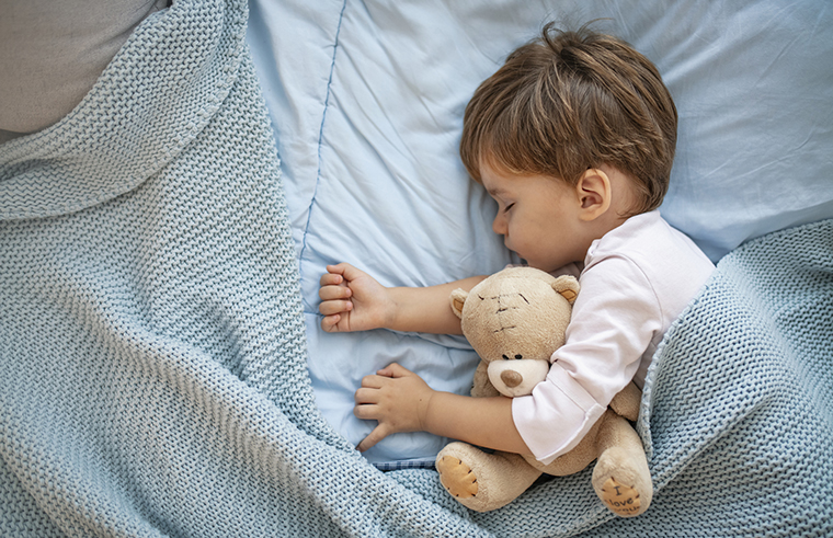 Toddler boy asleep in bed with teddy bear - feature
