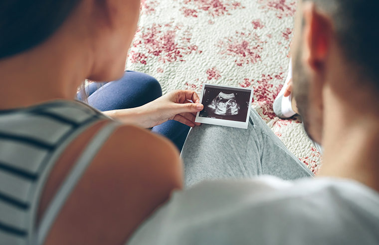 Couple holding ultrasound of baby - feature