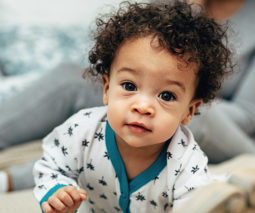 Curly haired baby in onesie - feature