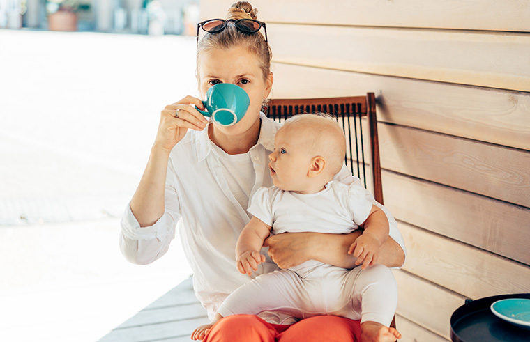 Mother drinking coffee while holding baby - feature