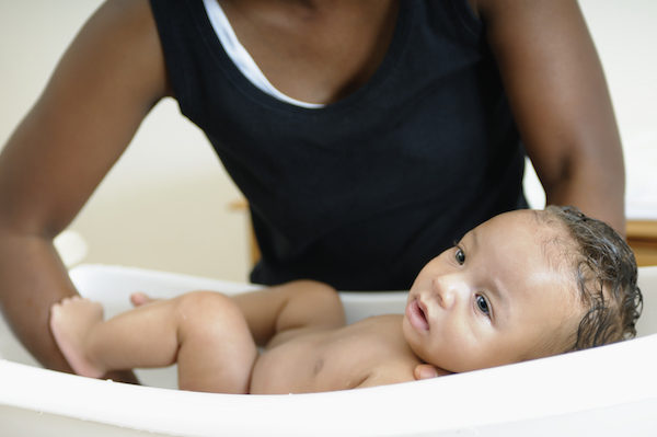 mother bathing baby in portable bathtub