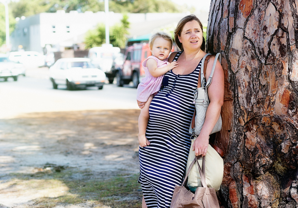 Exhausted pregnant woman carrying toddler and shopping looks stressed