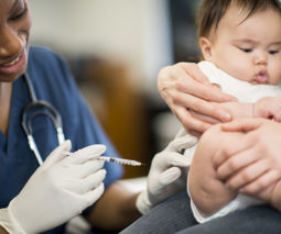 Asian baby getting vaccination needle given by a nurse - feature