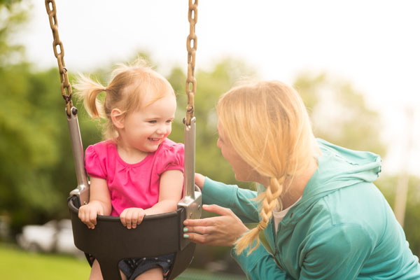 Babysitter with little girl on swing