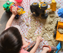 Toddler boy playing with trucks and sand - feature