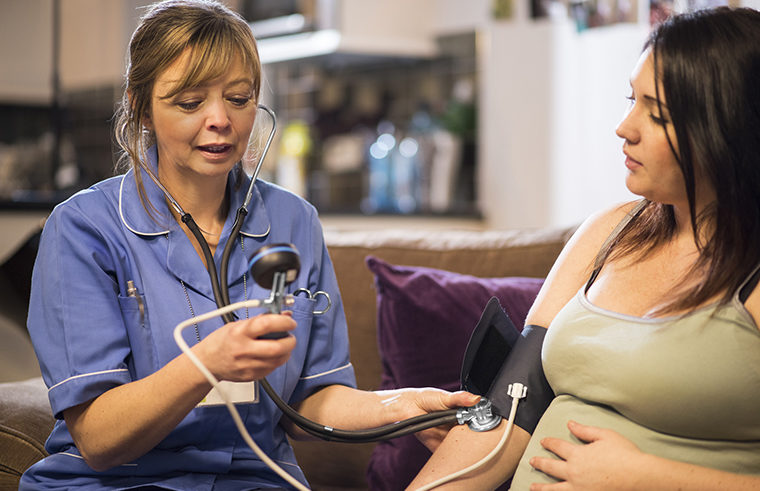 Midwife checking pregnant woman's blood pressure