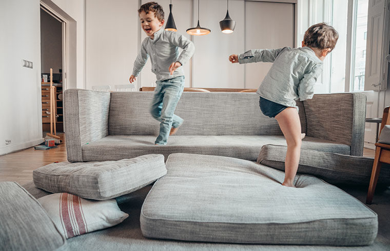 Two boys playing on couch with cushions - feature