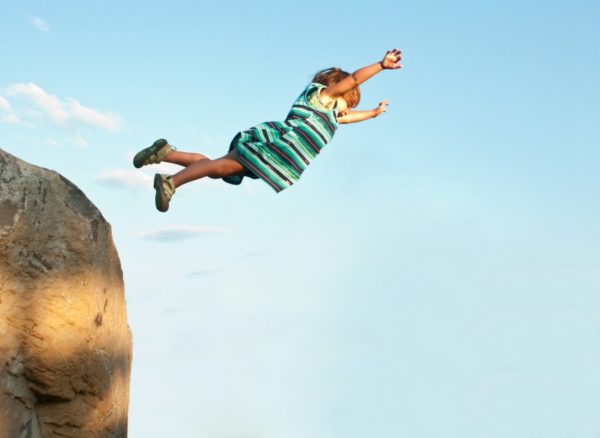 young child jumping off rock