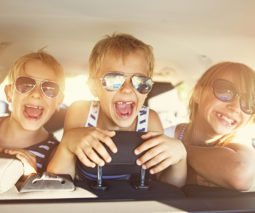Three children in backseat of car playing - feature