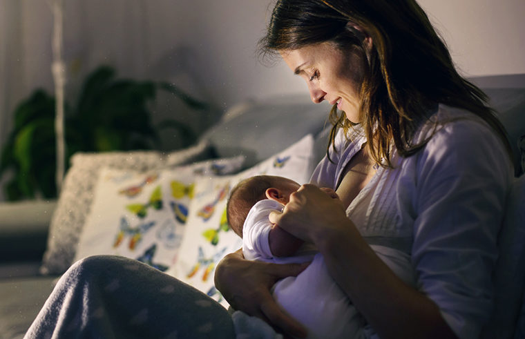 Mother breastfeeding baby at night - feature