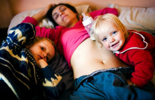Mother asleep with two kids lying beside her