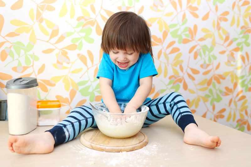 Little boy with hands in mixing bowl