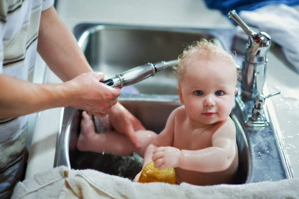 Baby being bathed in kitchen sink