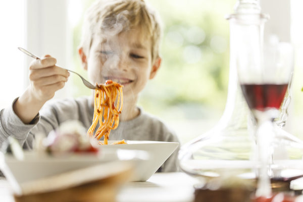 Boy eating spaghetti at table.
