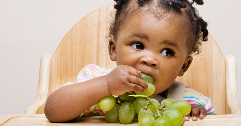 Baby girl eating grapes