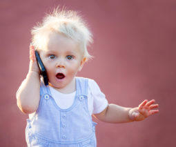 Baby talking mobile phone outdoors - feature