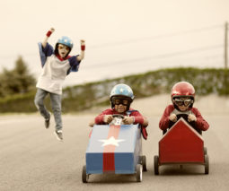 Three boys playing in go-carts racing - feature