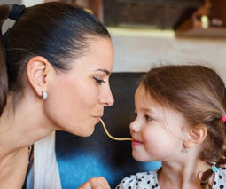 Mother and toddler girl sharing spaghetti