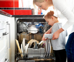 Mother helping toddler load dishwasher - feature