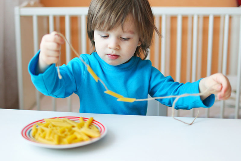 Boy making pasta necklace