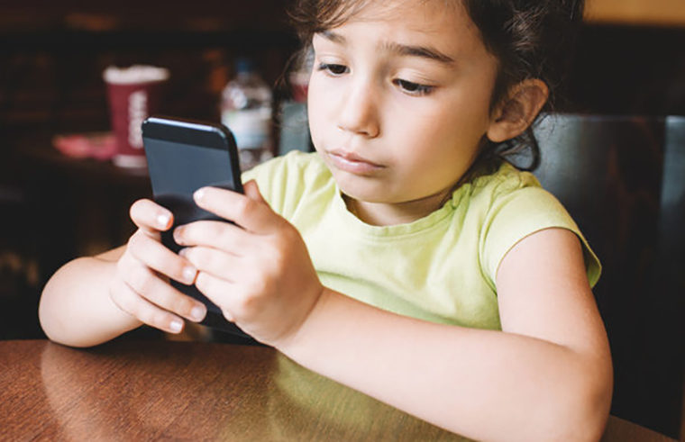 Young girl playing with mobile phone - feature