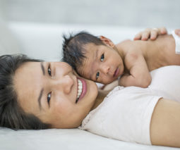 Asian mother holding newborn baby on her chest - feature