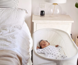 Baby asleep in crib next to parent's bed - feature
