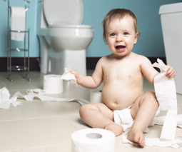 Baby on bathroom floor with toilet paper - feature