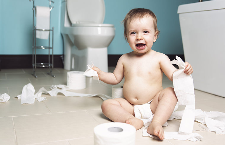 Baby on bathroom floor with toilet paper - feature
