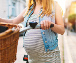 Pregnant woman pushing bicycle - feature
