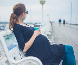 Pregnant woman sitting with coffee cup - feature