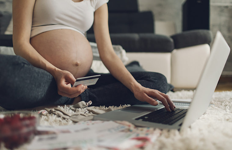 Pregnant woman sitting on floor with laptop computer and credit card - feature
