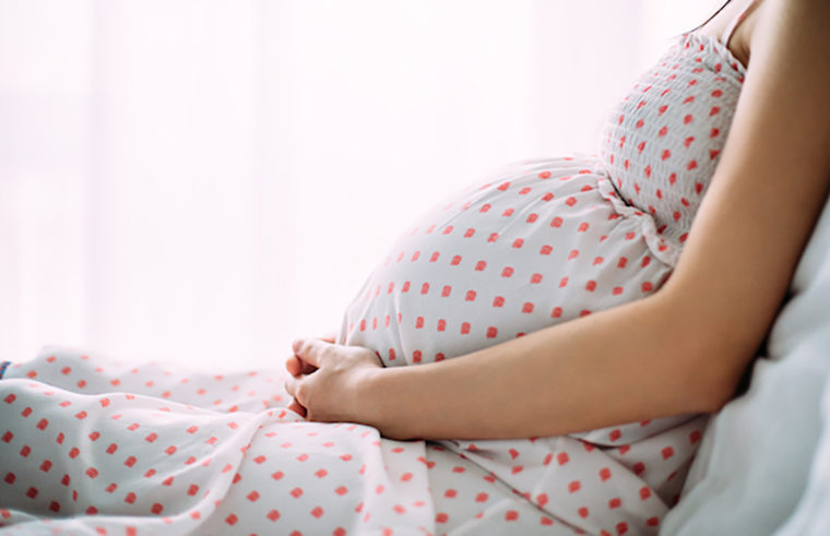 Pregnant woman sitting in a spotty dress - feature