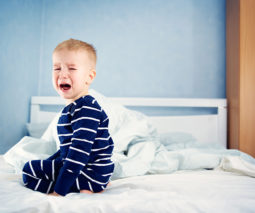 Tired toddler crying in bed - feature