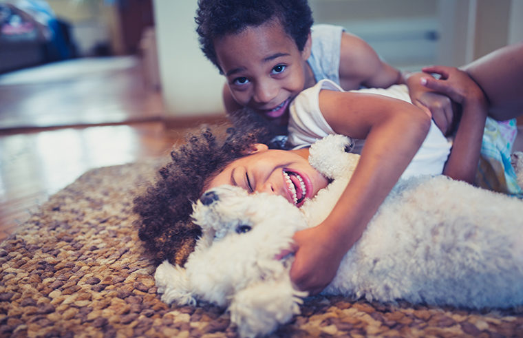 Two kids playing with dog on floor - feature