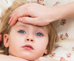 Sick child mother's hand on forehead checking temperature - feature