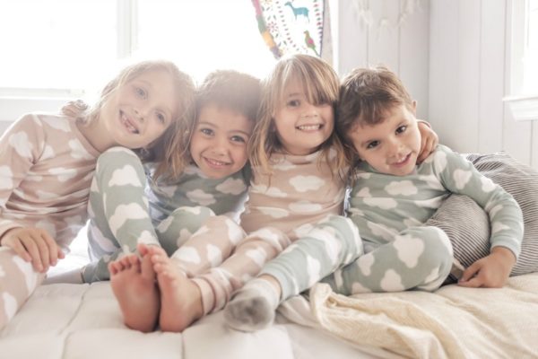 four kids in pyjamas sitting on a bed