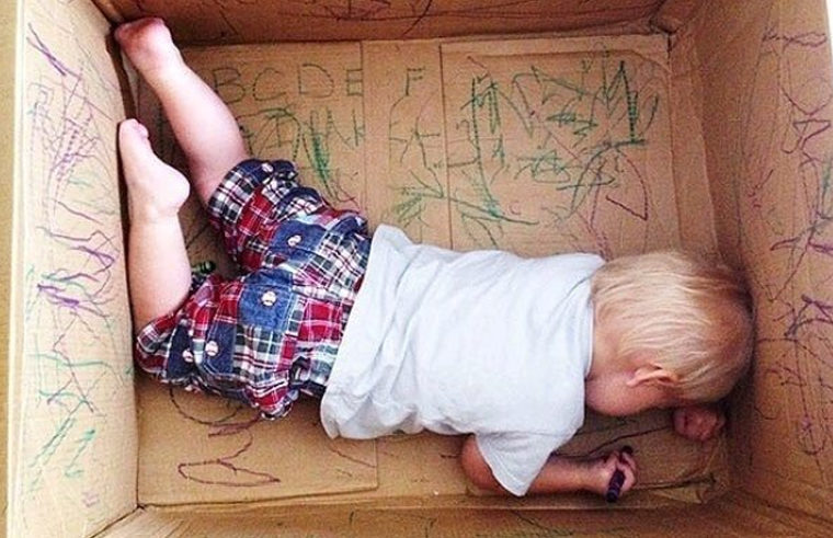 Toddler drawing in cardboard box