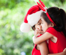 Two girls with Christmas hats hugging - feature